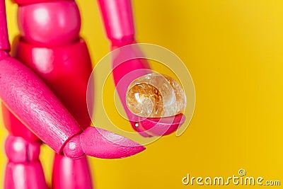 Amber semiprecious piece of stone in hands of pink wooden manikin Stock Photo