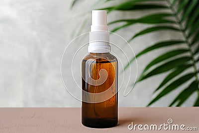 Amber spray bottle mockup with tropical green leaf. Herbal medicine packaging design, natural organic cosmetic package Stock Photo