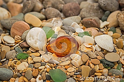 Amber stone. Mineral amber. Rosin yellow amber. Sunstone on a beach of pebbles. Stock Photo