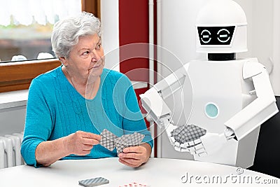 Ambient assisted living service robot is playing a card game with a senior adult woman Stock Photo