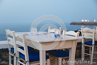 Ambient atmospheric evening on Greek coast, white tables in rest Stock Photo