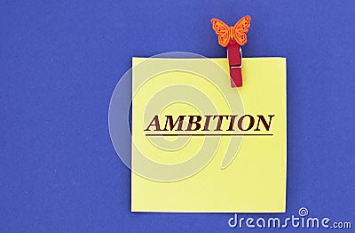 AMBITION - word on a yellow piece of paper on a blue background Stock Photo