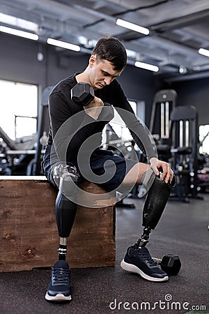 ambitious active young man in stylish sportswear doing exercises with dumbbells Stock Photo
