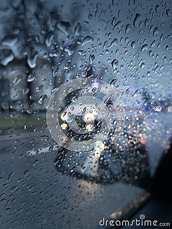 Ambulance in foreground with rain drops in focus photographed from a car while waiting in traffic. Moody vibes. Stock Photo