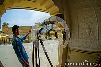 Amer, India - September 19, 2017: Unidentified man manipulating a golden telescope inside of the palace in Amer, in Editorial Stock Photo