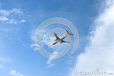 American Airlines plane is flying in blue sky on sunny day. Travel, vacation, air transportation. Editorial Stock Photo
