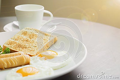 American breakfast and hot coffee in a white ceramic coffee cup on a wooden table with warm morning sunshine Stock Photo