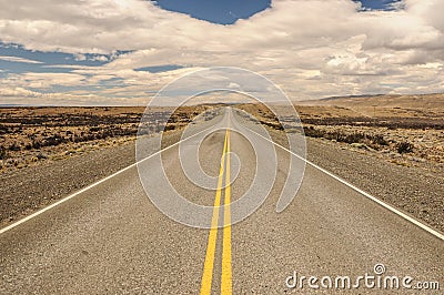 American empty desert asphalt road from low angle with mountains and clouds on background. El Calafate to Puerto Natales. Stock Photo