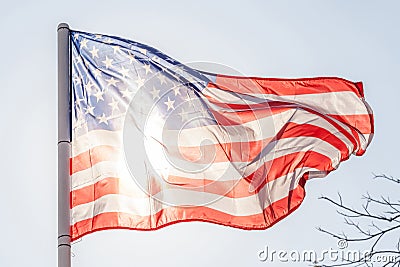 American flag flapping on sky with sunlight from back. Stock Photo