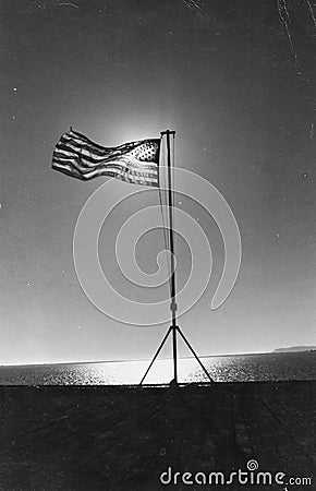 American flag on the flight deck of the USS Alamo, LSD-33, with the sun shining through the field of stars Stock Photo