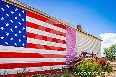American flag, wall of a house, old fashioned truck on Route 66, is attracting visitors from all of the world Arizona Stock Photo