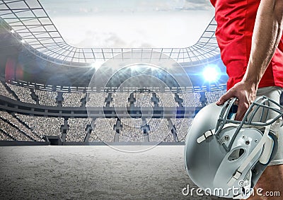 American football player standing with helmet against digitally composite stadium Stock Photo