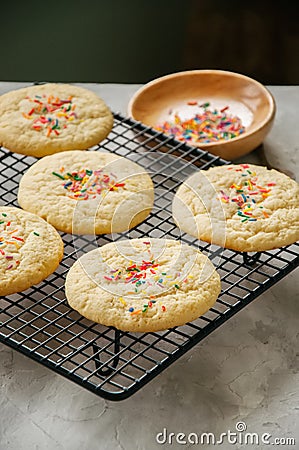 American style round cookies with confetti (shortbread) on a wire rack on a grey stone backdrop. Stock Photo