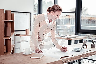 Amicable good-looking fashion designer feeling inspired correcting sketches Stock Photo