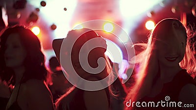 Amigos que bailan en el proyector en un disco en un club nocturno Muchachas que bailan en una muchedumbre de gente Amigos que bailan en el proyector en un disco en un club nocturno Muchachas que bailan en una muchedumbre de gente