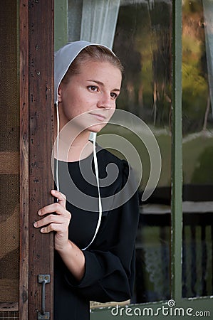 Amish Woman Looks out Screen Door Stock Photo