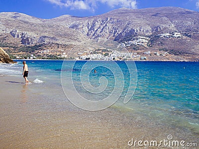 Amorgos, Greece-August 2,2017.The beutiful beach of Psili Ammos, with crystal clear waters and the port of Aegiali in the back. Editorial Stock Photo