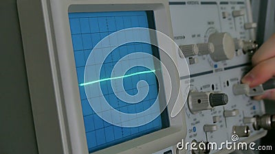 Amplitude Diagram on the oscilloscope. A man presses the buttons on the device. The geometric line changes shape Stock Photo