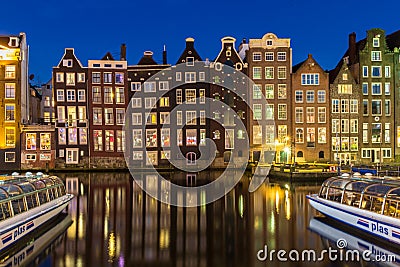 Amsterdam canal houses on the Warmou straat reflected in the water of Damrak Editorial Stock Photo