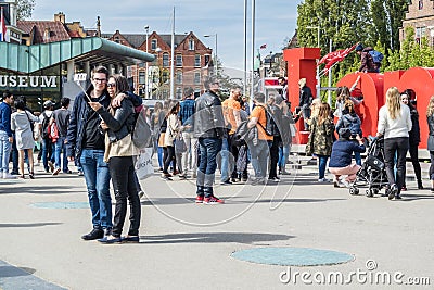 Amsterdam , Netherlands - April 31, 2017 : Couple taking selfies while people walking around the I Amsterdam letters in Editorial Stock Photo