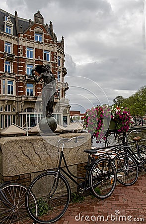 AMSTERDAM- NETHERLANDS, on JULY 12, 2017.Cycles and flowers near Statue of Lady Fortune, Amsterdam, Netherlands, Europe. Editorial Stock Photo