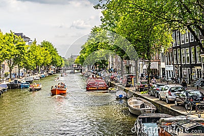 Amsterdam, Netherlands - July 18, 2019: Life on the canals. Barges on the canal and many vehicles on the side streets Editorial Stock Photo