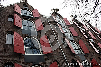 Amsterdam, windows in row with opened red shutters, shooting from below in historical building Stock Photo