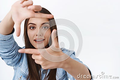 Amused, inspired fascinated young creative female searching perfect angle, making hand frames, looking through to find Stock Photo