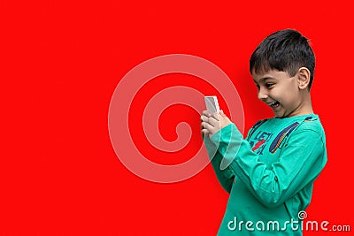 Amused young kid playing games on smartphone - posing at studio Stock Photo