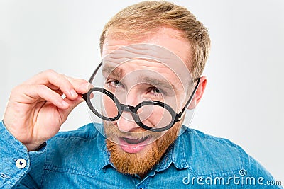Amusing happy man with beard looking over his round glasses Stock Photo