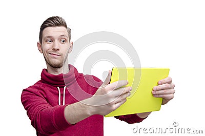 Amusing young guy holding tablet pad and looking at the screen Stock Photo