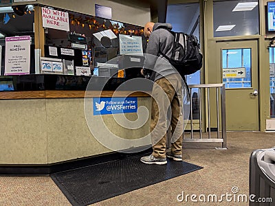 Anacortes, WA USA - circa November 2022: Wide view of a man purchasing a ferry ticket inside a Washington State Ferry terminal Editorial Stock Photo