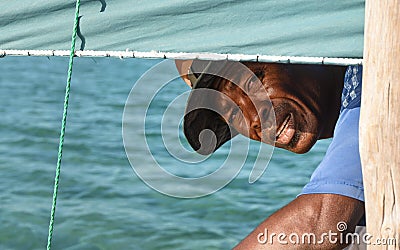 Anakao, Madagascar - May 03, 2019: Unknown Malagasy fisherman looking back under main green sail of his piroga small fishing boat Editorial Stock Photo