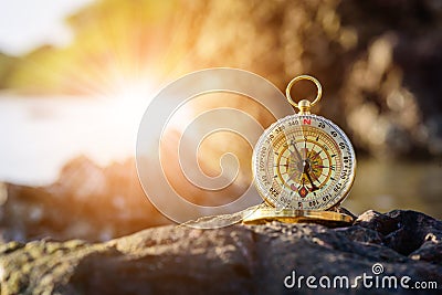 Analogical compass abandoned on the rocks with blurred sea Stock Photo