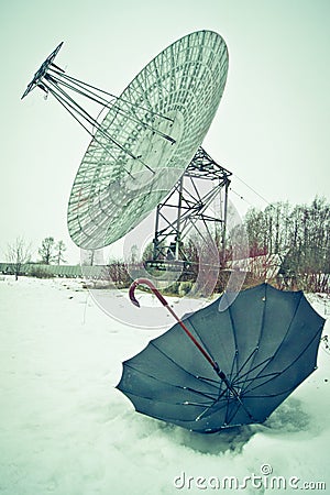 Analogy of black umbrella on the snow with a big dish antenna Stock Photo
