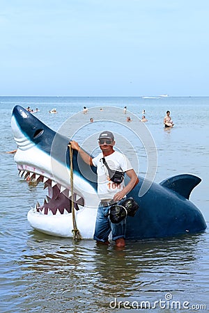 Anapa, Russia - 5 August 2016: illegal entrepreneur offers on beach in Anapa to be photographed with toy shark head for memorable Editorial Stock Photo