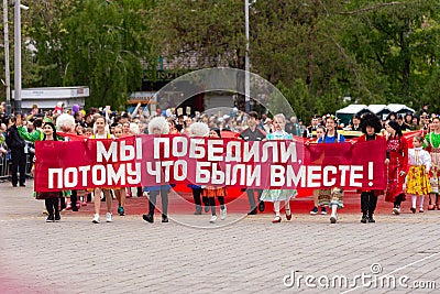 Anapa, Russia - May 9, 2019: Young people in folk costumes carry a sign Editorial Stock Photo