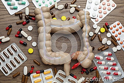 Anatomical model of large intestine and many different pills on wooden background, flat lay Stock Photo