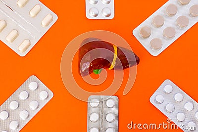 Anatomical models of liver surrounded by six blister packs with white pills inside six-pointed star in corners of image on orange Stock Photo