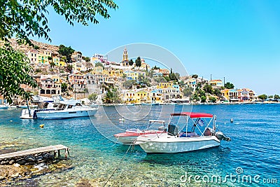 Anchored boats and colorful neoclassical houses in bay of Symi Symi Island, Greece Stock Photo