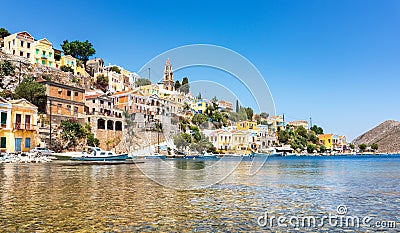 Anchored boats and colorful neoclassical houses in bay of Symi Symi Island, Greece Stock Photo