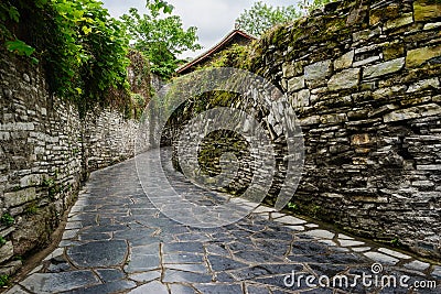 Ancient alley with stone-stacked walls in cloudy spring afternoon Stock Photo