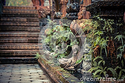 Ancient Asian style garden alley with old column overgrown with tropical plants and blurred background Stock Photo