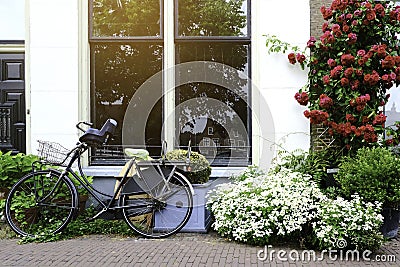 Ancient bikes parked in front of the house. Bicycle leaning on the big windows at roadside Stock Photo