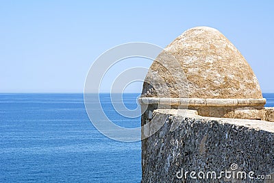 Ancient brown stone wall near the blue sea and blue sky Stock Photo