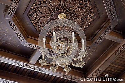 Ancient chandelier on wooden carving ceiling background. Travel Stock Photo