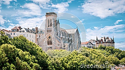 Ancient church with its majestic structure surrounded by lush green trees in Biarritz, France Editorial Stock Photo