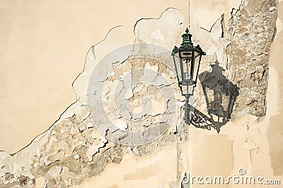 An ancient dark green squiggly lantern casting a cloud over a grungy house wall in Prag Stock Photo