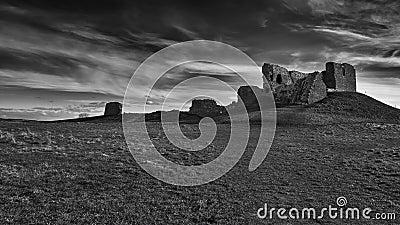 Ancient Duffus castle ruins atop a rocky hill, surrounded by clouds and overcast skies Stock Photo