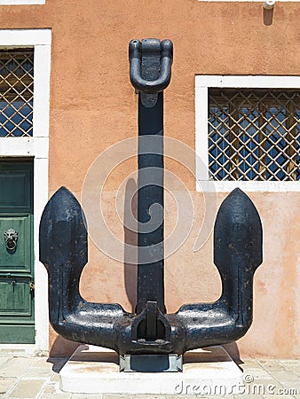 Ancient iron black anchor over red wall background Stock Photo
